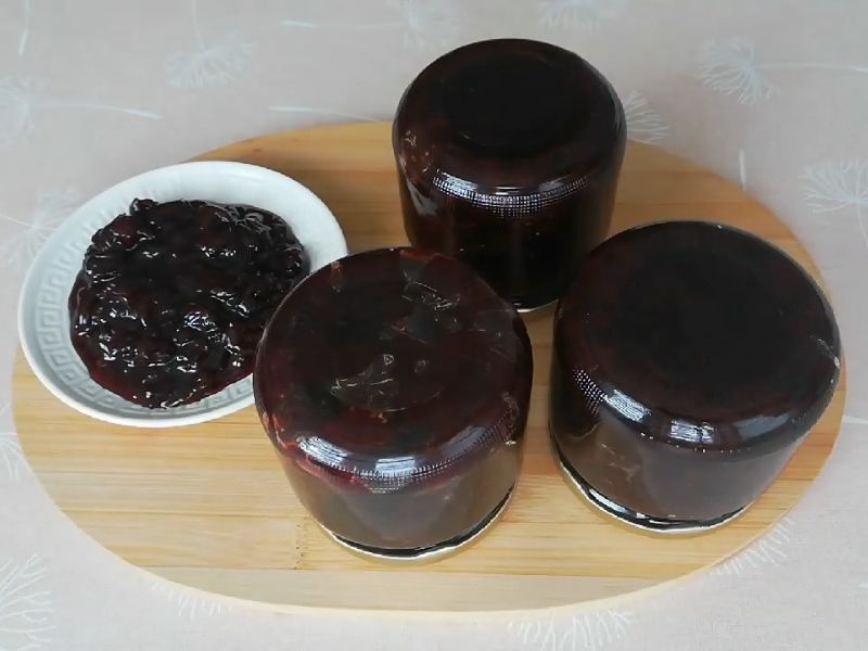 slatko od trešanja u tri tegle okrenute naopako na drvenoj dasci i servirano u malu belu činiju pored